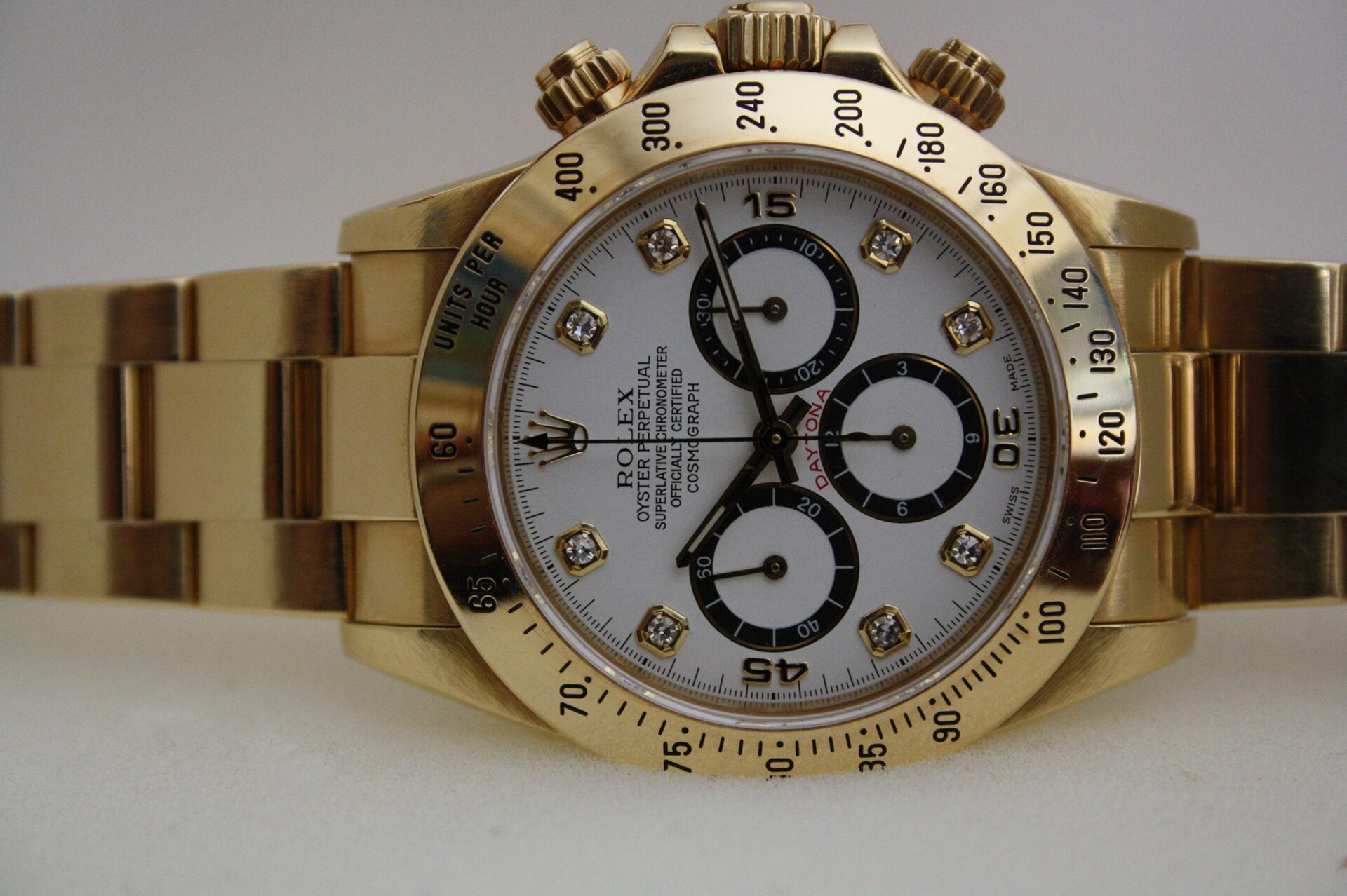 A Rolex Cosmograph Daytona reference 16528 in yellow gold, photographed from directly above against a plain ground, its three chronograph sub-dials and tachymeter bezel clearly visible.